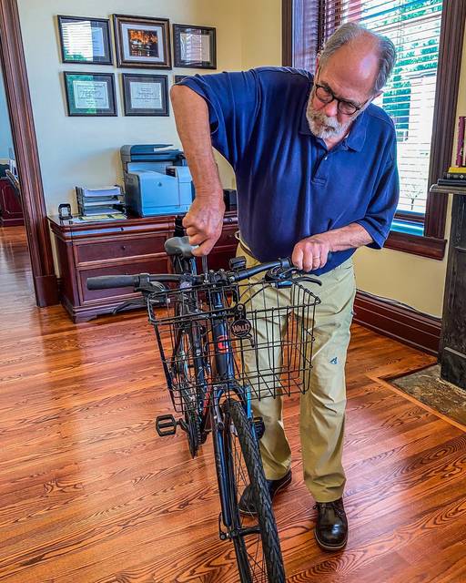 Volunteer Dan Crum helps install baskets donated by Wald Manufacturing on bicycles tourism will soon loan to visitors.